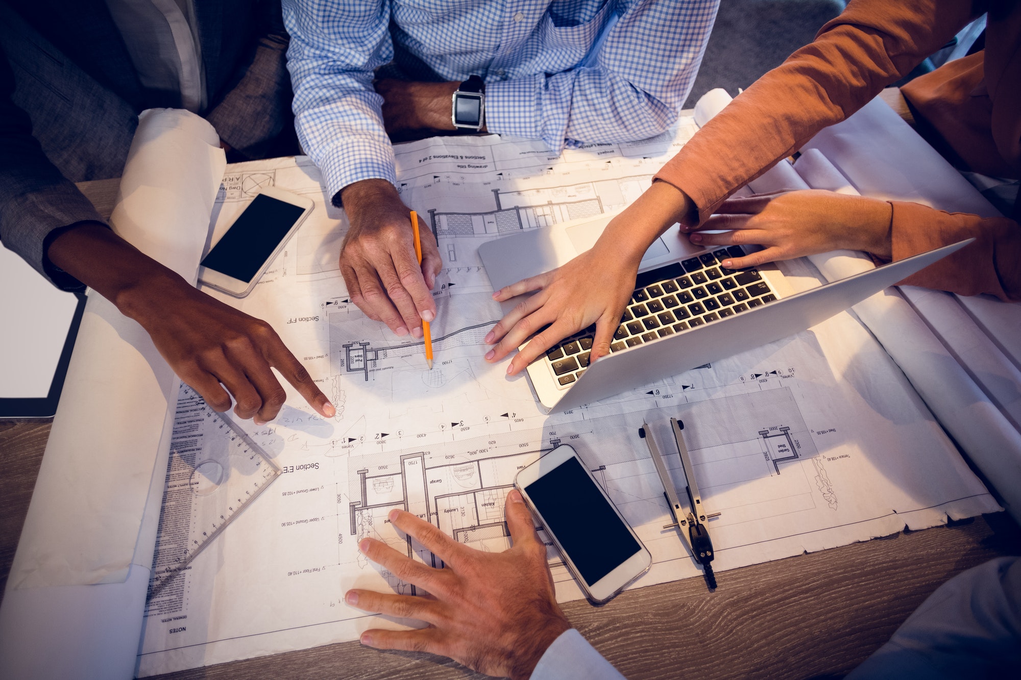 Four architects discussing blueprints in meeting